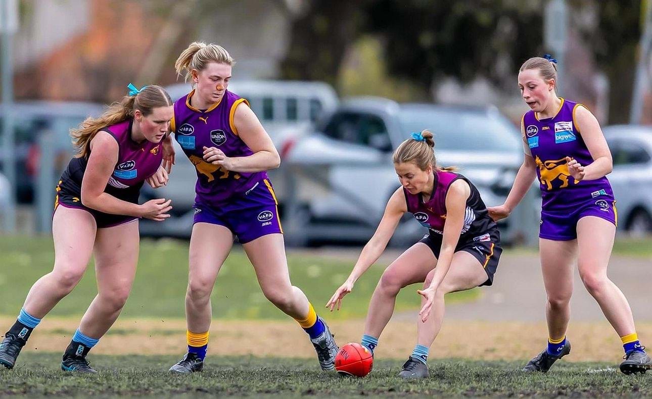 Nicky Nowlan bends to collect a ground ball, supported by Ivy Compton at left